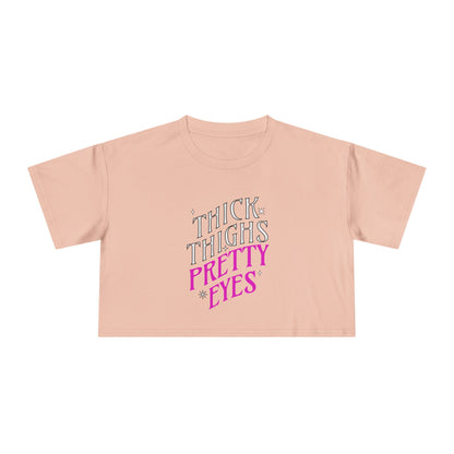 Pink crop top with text 'THICK THIGHS PRETTY EYES' on a white background