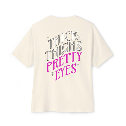 Beige t-shirt with 'Thick Thighs Pretty Eyes' text on a white background
