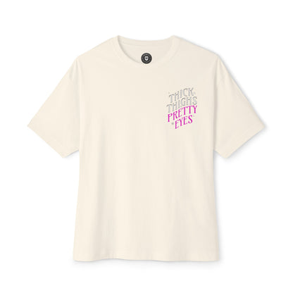 Beige t-shirt with 'THICK THIGHS PRETTY EYES' text on a white background