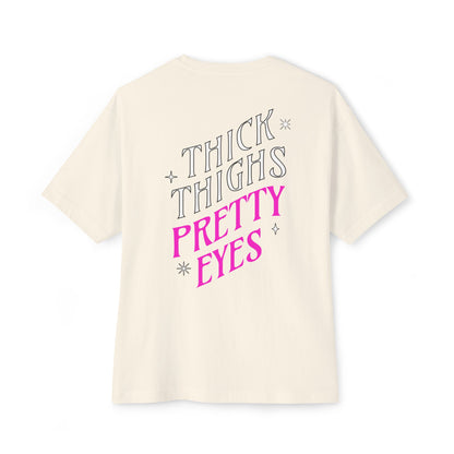 Beige t-shirt with 'THICK THIGHS PRETTY EYES' text on a white background