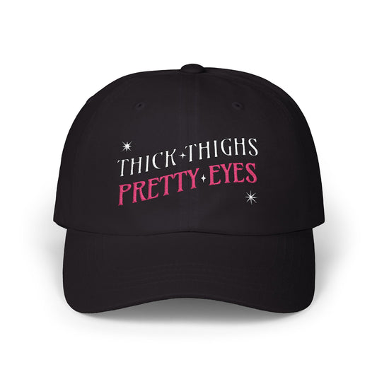 Black cap with 'THICK THIGHS PRETTY EYES' text on a white background